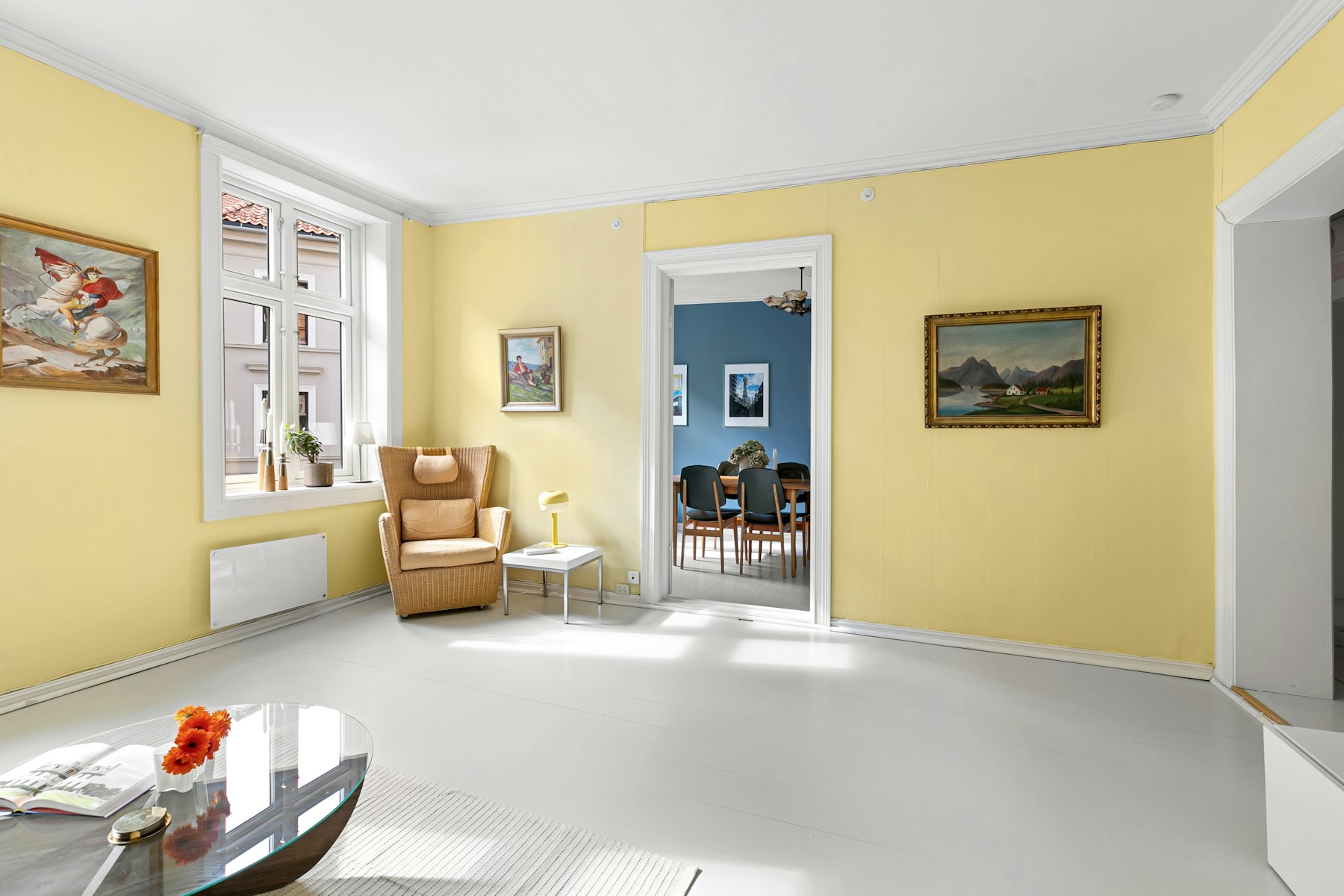 Sunlit living room with warm yellow walls and a contrasting blue dining room